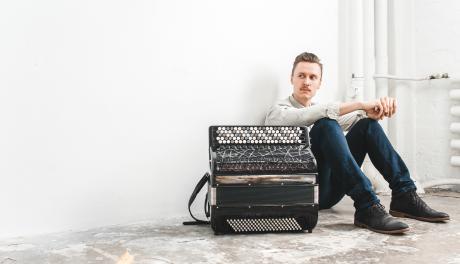 Muusikko istuu lattialla harmonikka edessään