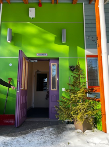 Vierassisäänkäynnin ovi on violetti ja seinät kirkkaan vihreät.