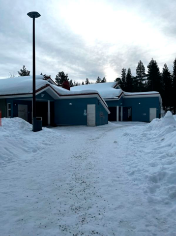 Kulkyväylä pihassa on luminen. Kuvassa näkyy yksi pihavalaisin sekä sininen, matala päiväkotirakennus.