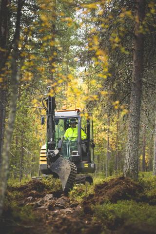 KKaivinkone ja kuljettaja metäsmaisemassa reittipohjaa tekemässä.