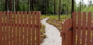 Kittilän pieneläinhautausmaan portti ja hautausmaan käytävä, taustalla alueen metsää.