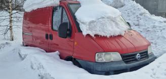 punainen auto osittain lumen alla