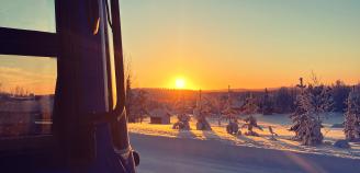 Kuvistuskuva, kirjastoauton kulma ja aurinko taivaanrannassa talvella taustalla