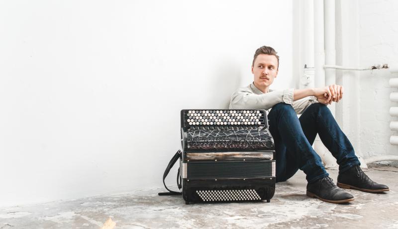Muusikko istuu lattialla harmonikka edessään