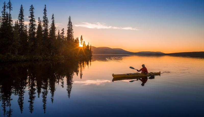 Kuvitskuva, meloja järvellä kesäisessä auringonlaskussa